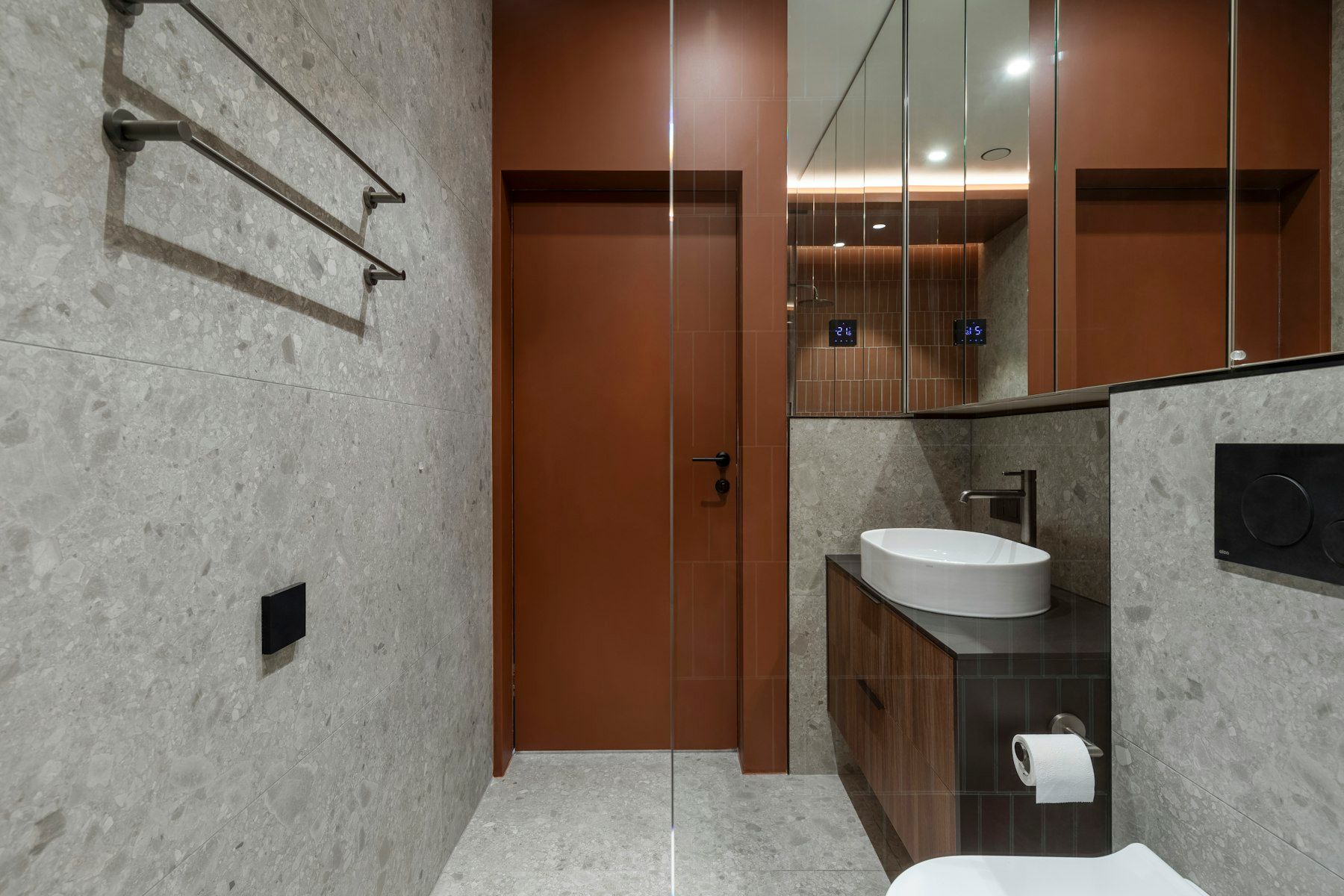 Bad mit Wandfliesen in Terrazzo-Optik, Waschtisch mit Holzunterschrank und Spiegelschrank