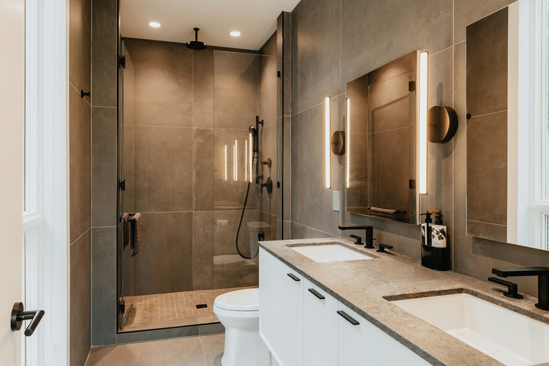 Bad mit großformatigen Wandfliesen, Walk-in-Dusche hinter Glas und Doppelwaschtisch
