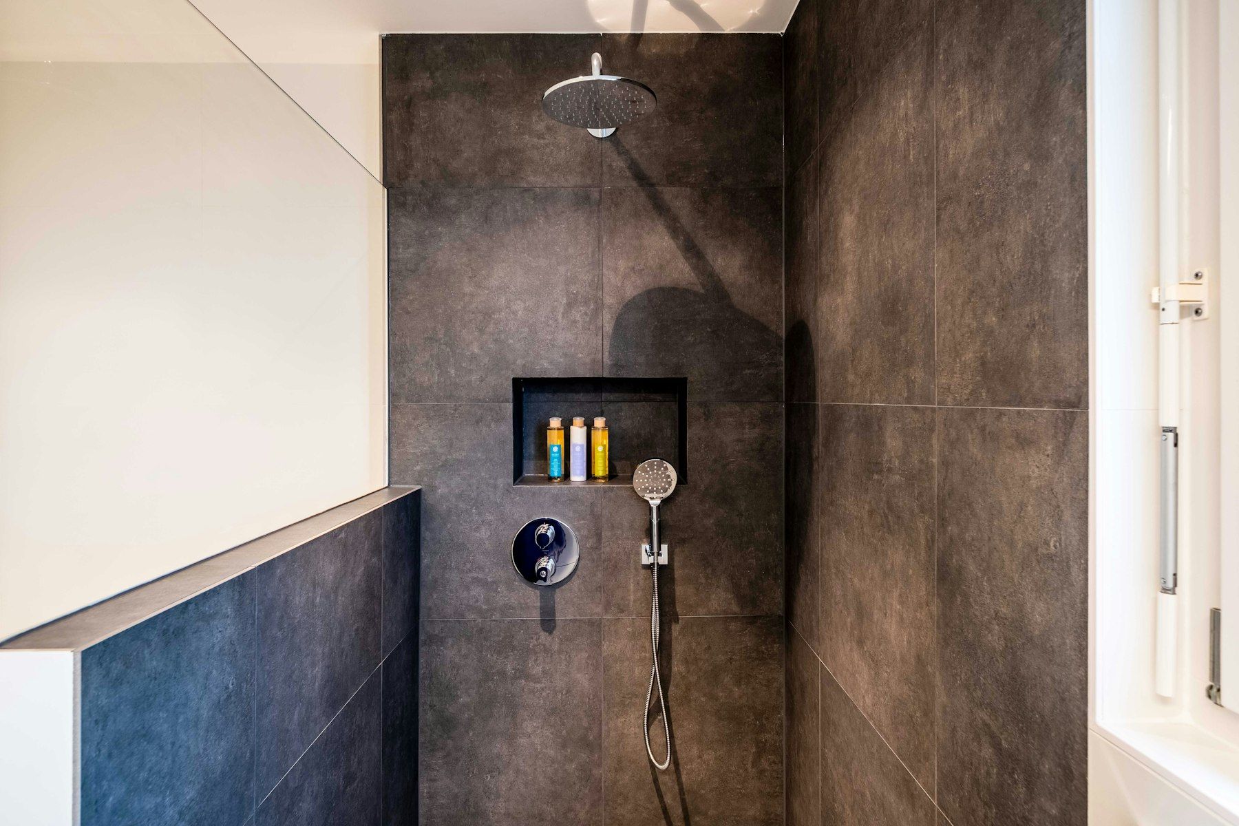 Dusche mit dunklen großformatigen Fliesen und eingelassener Ablagenische