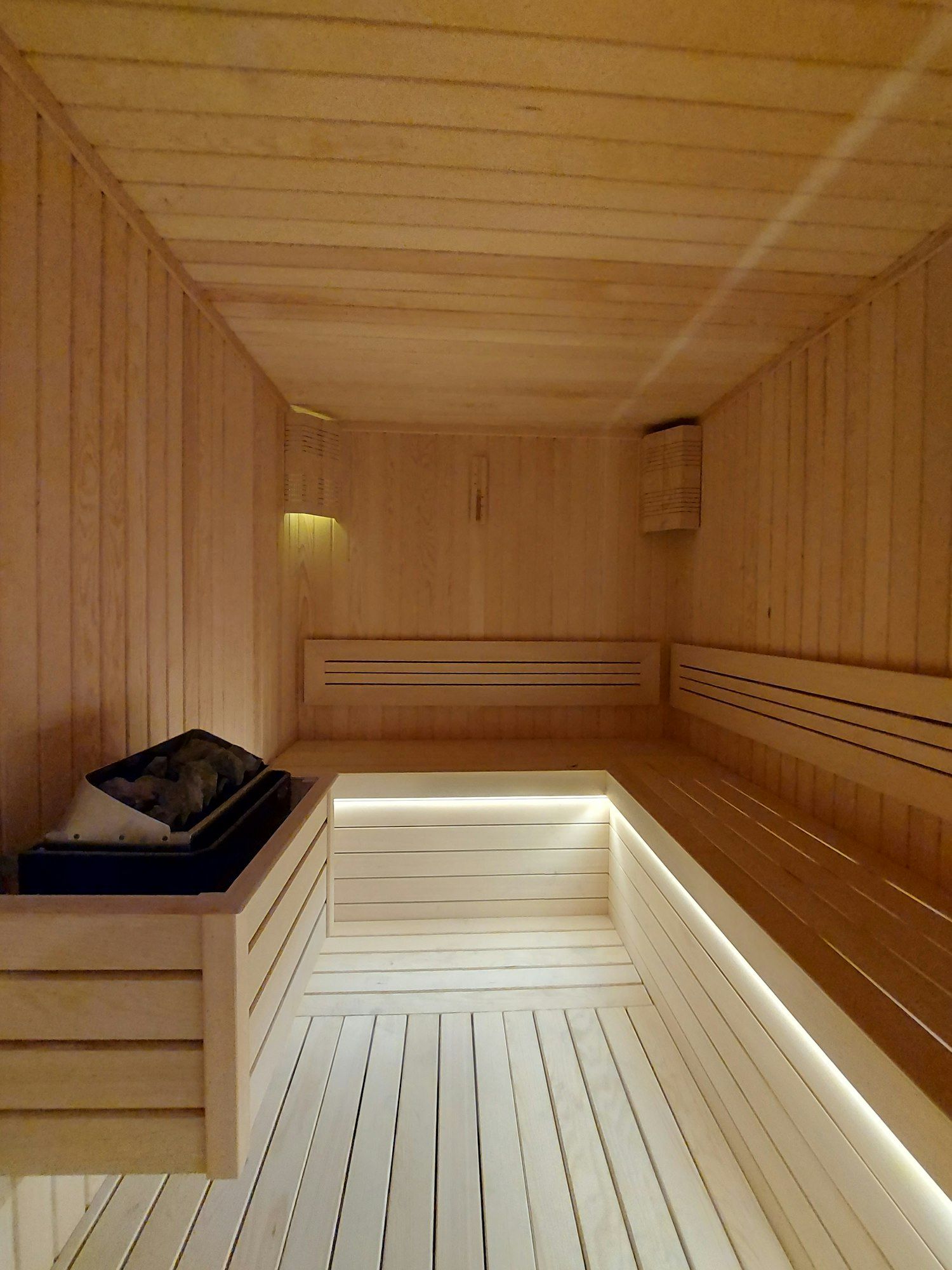 Moderne Sauna aus hellem Holz mit indirekter Beleuchtung unter der Bank
