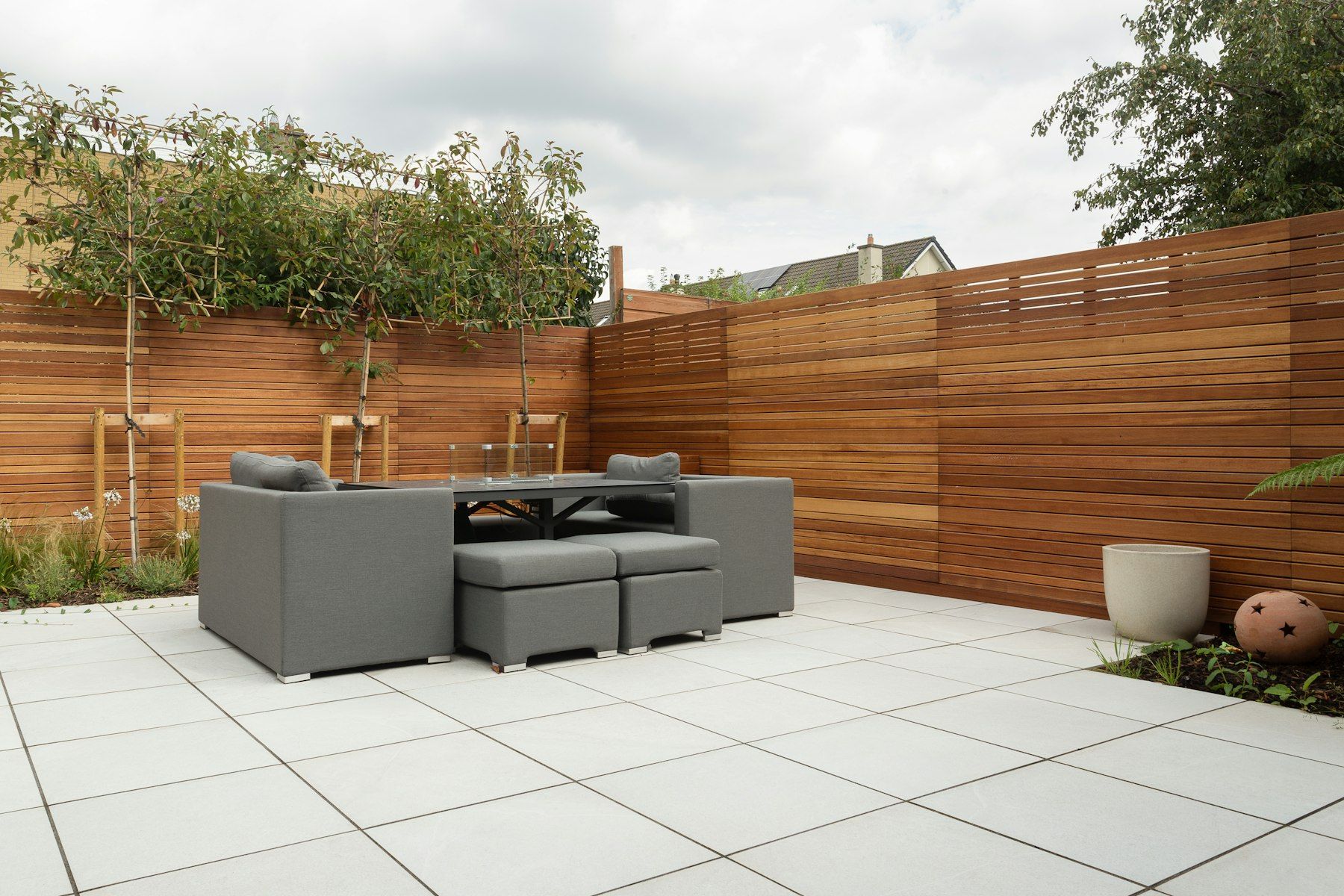 Terrasse mit großformatigen, hellen Feinsteinzeugplatten und Lounge-Möbeln