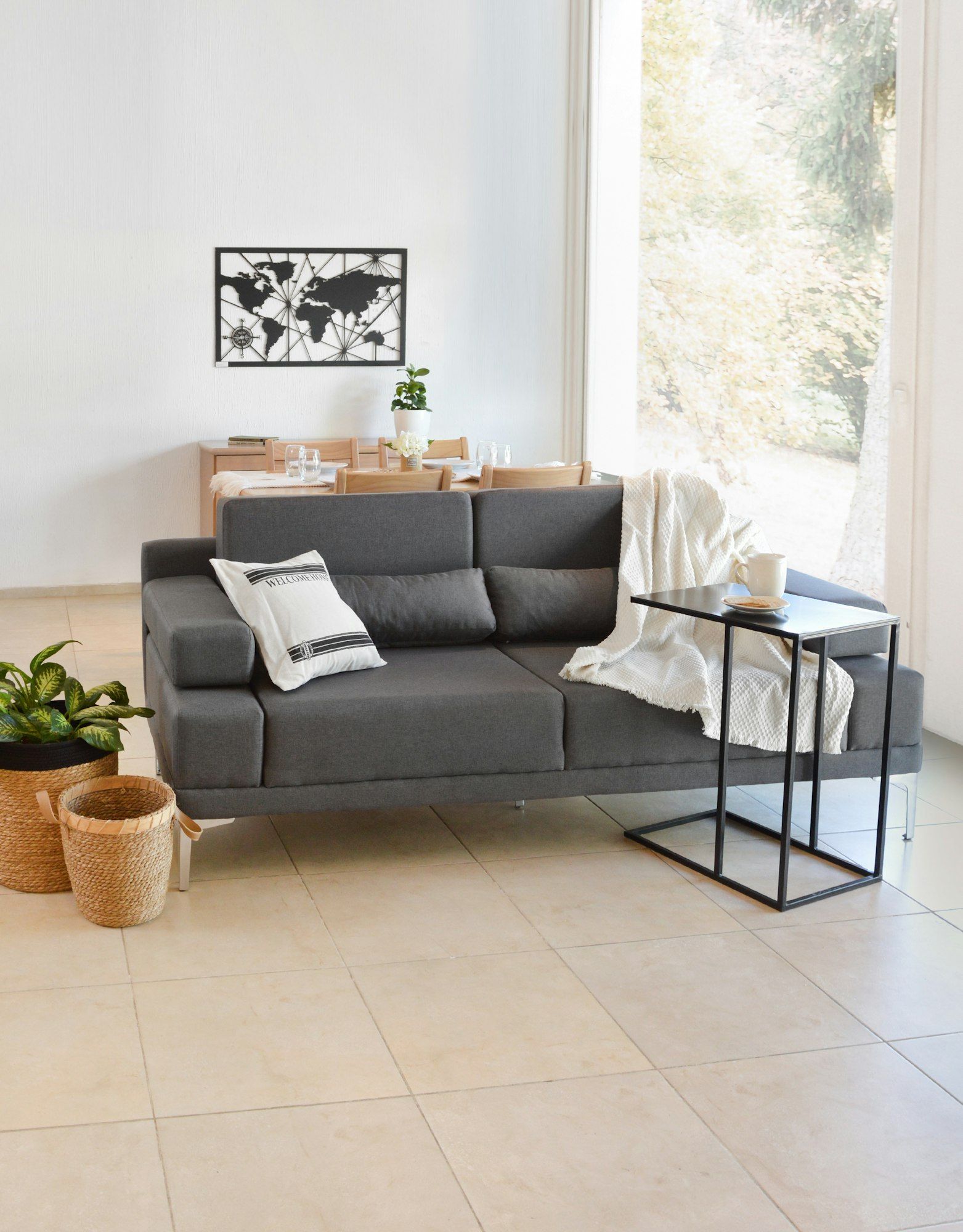 Wohnraum mit hellen, großformatigen Bodenfliesen und grauem Sofa